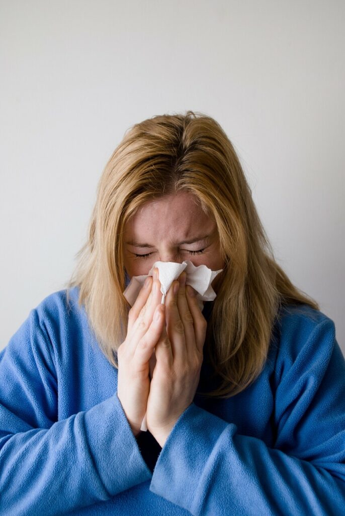 Chora kobieta wydmuchująca nos.