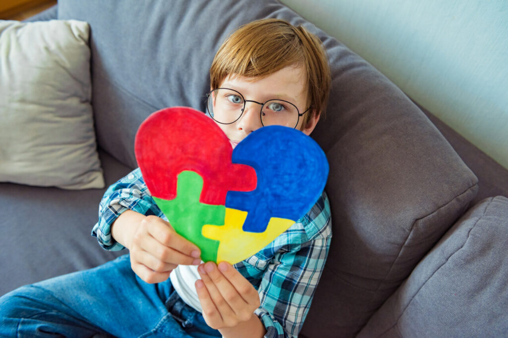 Młody chłopiec trzymający serce ułożone z puzzli.
