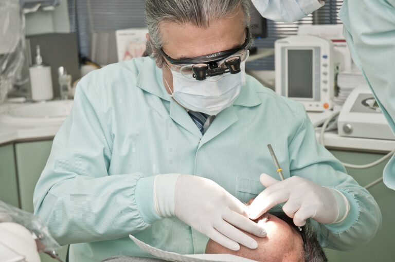 Dentysta obsługujący pacjenta siedzącego w fotelu, obrazek ilustrujący wpis blogowy o relacji tlenoterapii ze stomatologią.