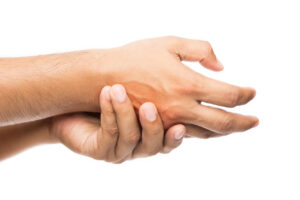 Zbliżenie na dwie dłonie, jedna obejmuje drugą, która w widoczny sposób stanowi źródło bólu.